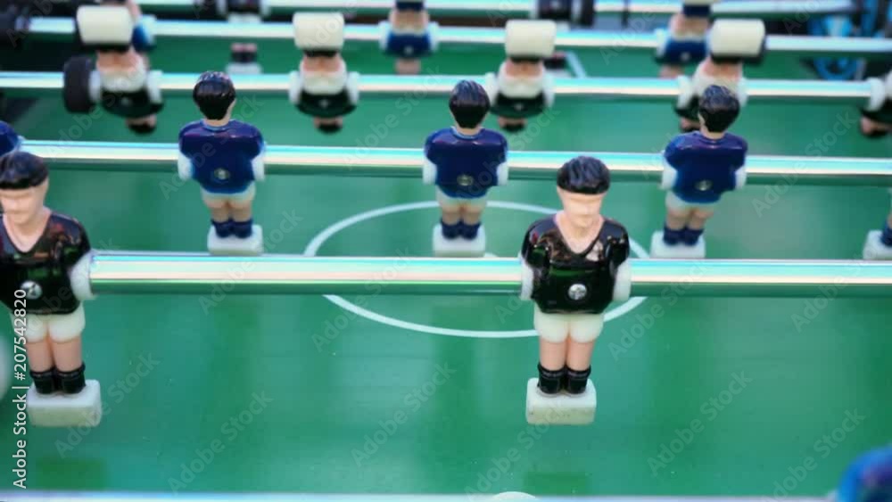 table football, ball game between blue and black on a green football field, close-up on the figures of players table football, ball game between blue and black on a green football field, close-up on the figures of players