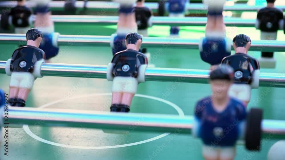 table football, ball game between blue and black on a green football field, close-up on the figures of players table football, ball game between blue and black on a green football field, close-up on the figures of players