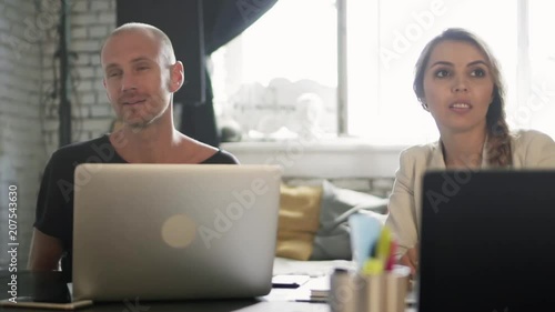 Two business partners in the office are asking for two cups of coffee. Co-workers during a coffee break are sitting at the table with their laptops