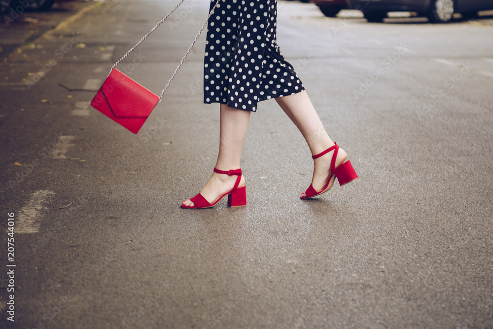 stylish woman in polka dot culottes and red high heel shoes holding a red  purse and crossing the road. street style fashion Stock Photo | Adobe Stock