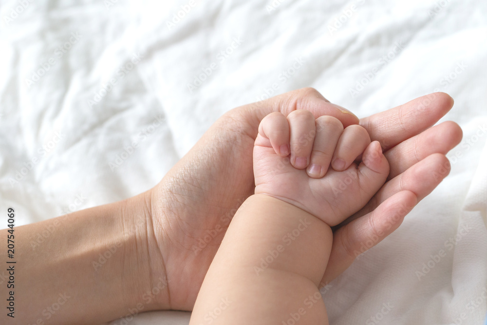 Mother uses her hand to hold her baby's tiny hand to make him feeling her love, warm, comfort and secure. Mother uses her hand to hold her baby's tiny hand to make him feeling her love, warm, comfort and secure.