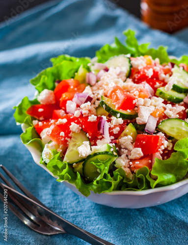 vitamin salad with tomato, cucumber, onion, lettucce and cottage cheese in white bowl on table