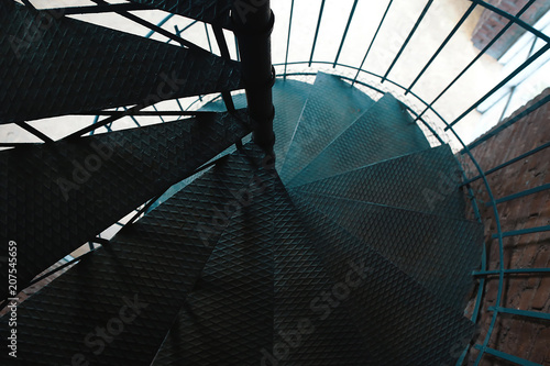 Forged iron twisted stairs with reflection on a red brick wall  selective focus