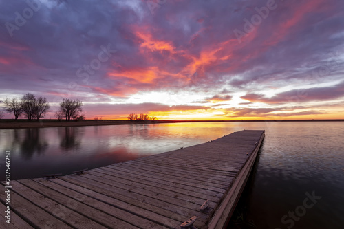 Fototapeta Naklejka Na Ścianę i Meble -  Sunrise or sunset on the fishing dock with colorful clouds reflecting in the lake