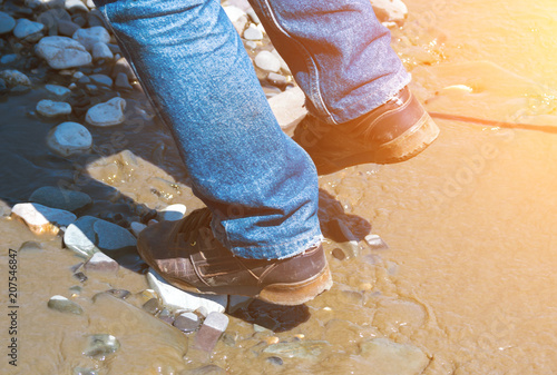 Crossing in shoes the river with dirty water photo