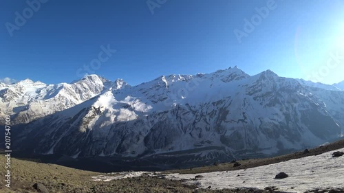 Snowy mountains view with the shining sun background