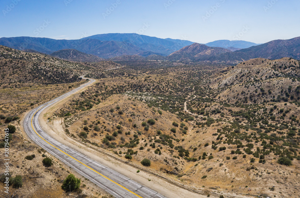 Empty asphalt road winds into the mountains of the Angeles National Forest in the Mojave Desert.