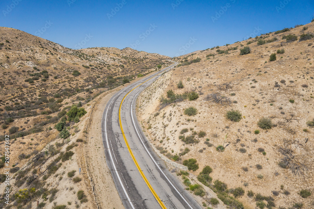 Asphalt highway bends around a curve in the empty wilderness of the American southwest.