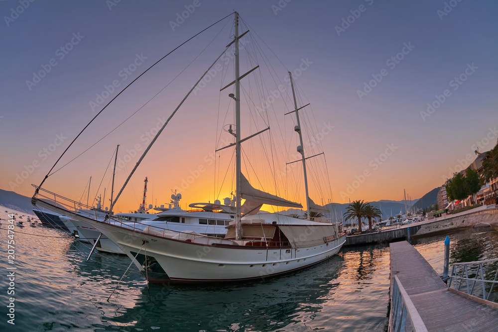 Sailing boats in marina at sunset.