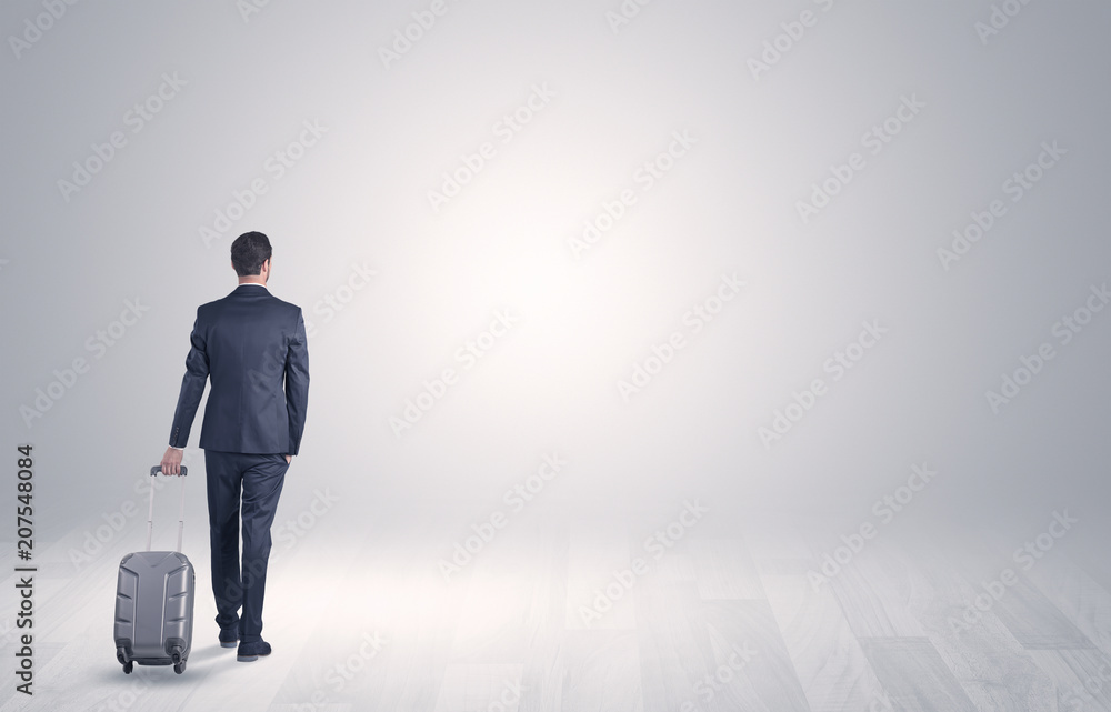 Young businessman in a white boundless space walking with back and luggage on his hand Young businessman in a white boundless space walking with back and luggage on his hand