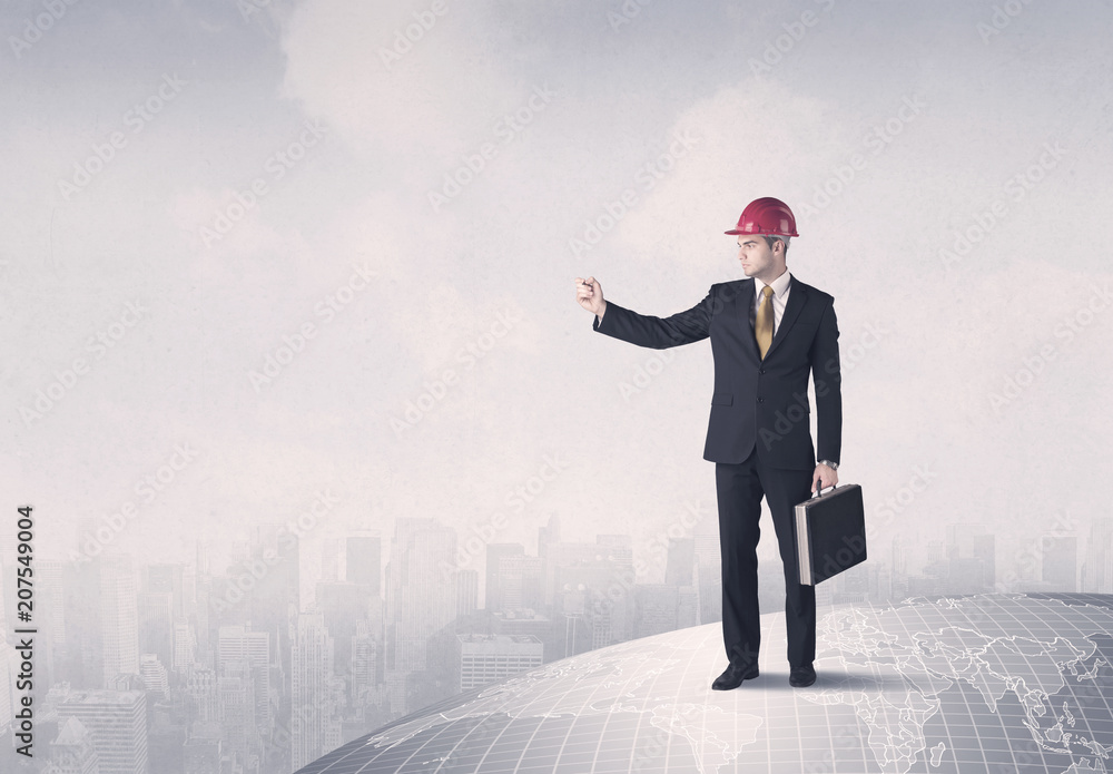 A happy, well dressed construction manager drawing with a pen and planning while standing on top of the earth concept. A happy, well dressed construction manager drawing with a pen and planning while standing on top of the earth concept.