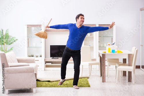 Young man cleaning floor with broom