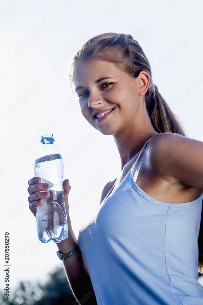Young beautiful sports girl drinking water during morning jogging Young beautiful sports girl drinking water during morning jogging