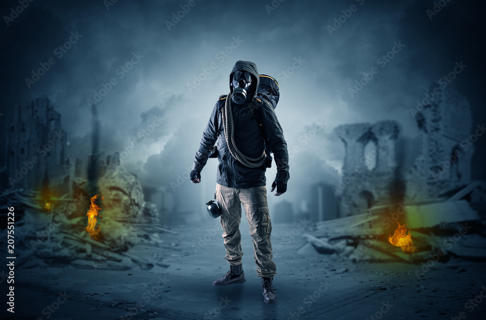 Fototapeta premium Destroyed place after a catastrophe with man in gas mask and weapon on his hand 