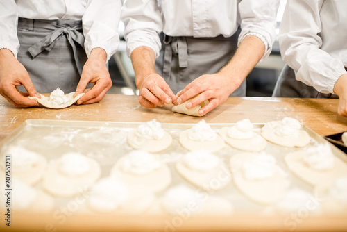 Workers forming raw buns with filling for baking at the manufacturing