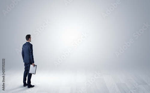 Man standing with his back in an empty room with object in his hand