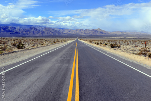 Driving on the open road in the desert with mountain backdrop