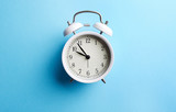 White vintage alarm clock on empty blue color background.