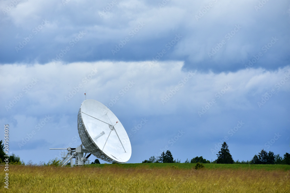 Large satellite dish in the field for receiving and transmitting tv signal and data transfer to the satellite, teleport