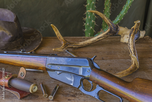 Western concept: old cowboy hat, hunting carbine,bullets, deer antlers on wooden background