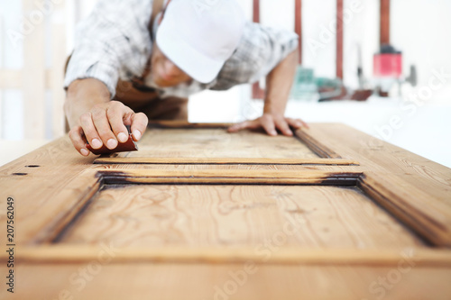 carpenter work the wood with the sandpaper