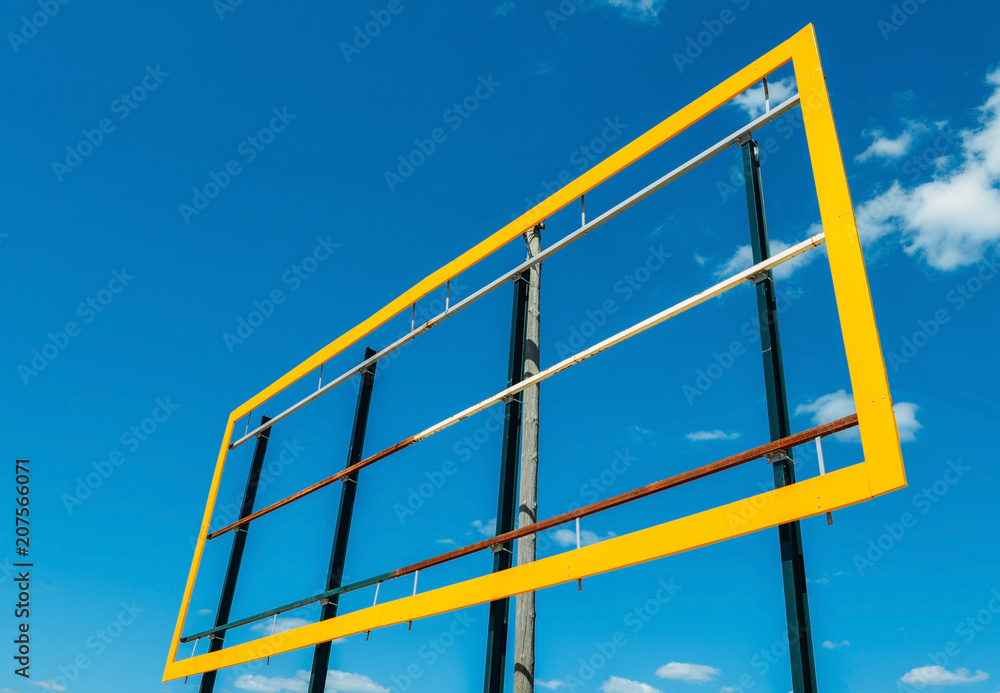 Blank billboard with yellow frame against a blue sky background