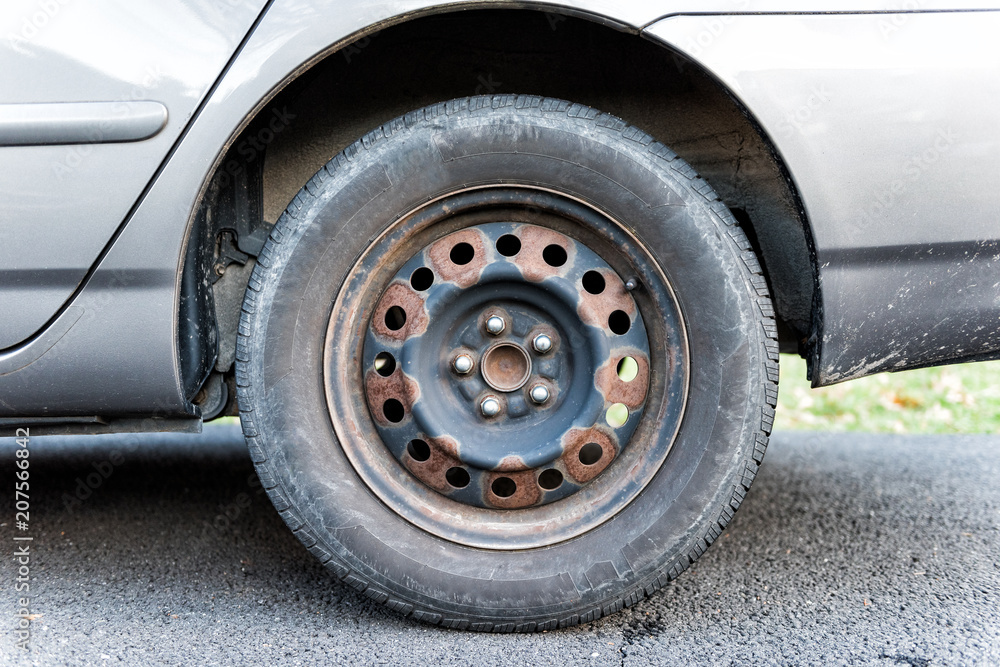 Closeup of tire wheel with missing cap cover on parked car, rust, hubcap Closeup of tire wheel with missing cap cover on parked car, rust, hubcap