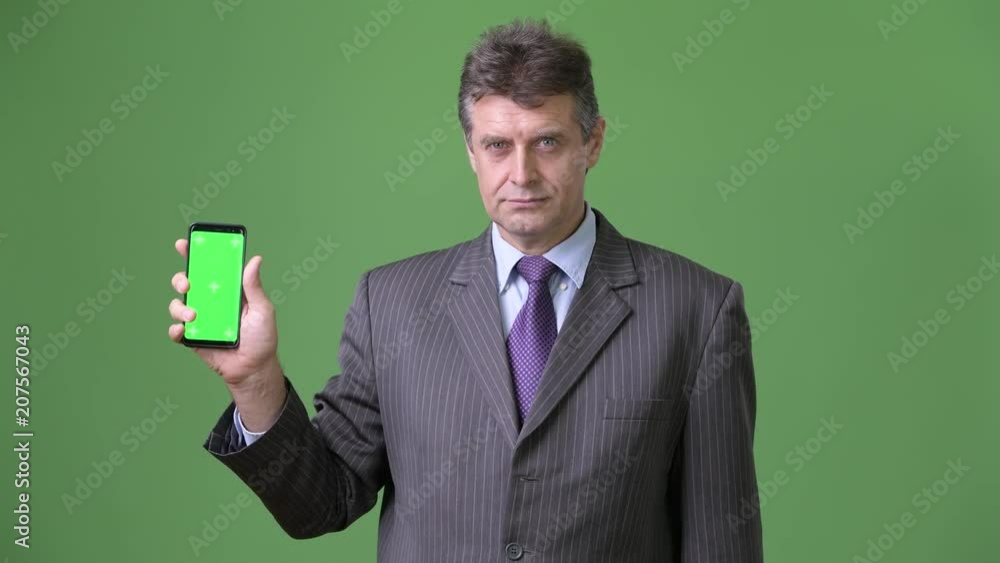 Mature handsome businessman against green background Mature handsome businessman against green background