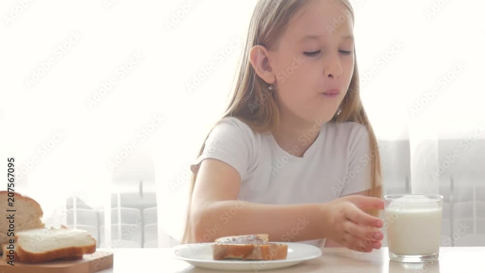 Child drinking milk and eating a sandwich. Girl holding a sandwich and she are to tasting. Child drinking milk and eating a sandwich. Girl holding a sandwich and she are to tasting.