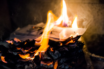 Burning fire paper, letters in indoor home interior fireplace with detail closeup of orange, blue flame