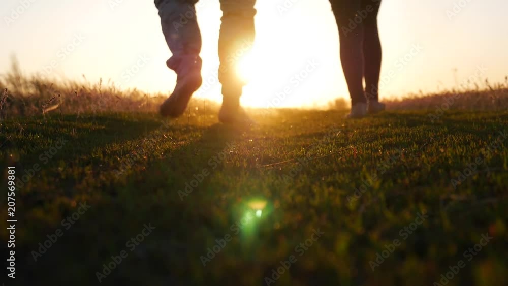 Go to the sunset, the lower angle. Legs barefoot walking on the grass against the sunset. Traveler's concept. Go to the sunset, the lower angle. Legs barefoot walking on the grass against the sunset. Traveler's concept.