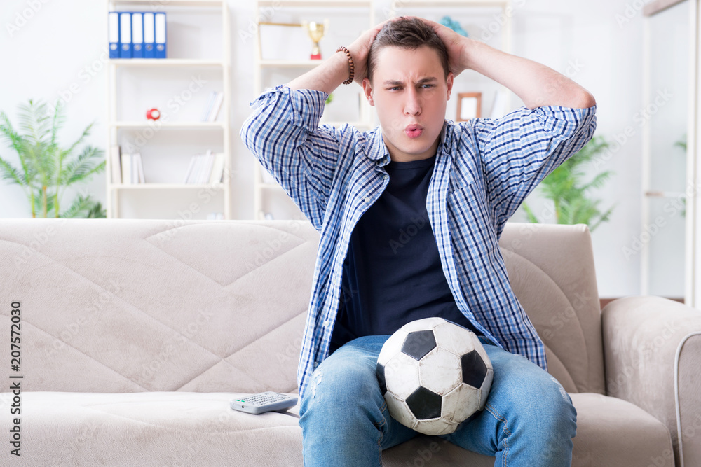 Young man student watching football at home Young man student watching football at home