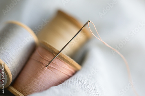 Photograph of spools of thread and a threaded needle 