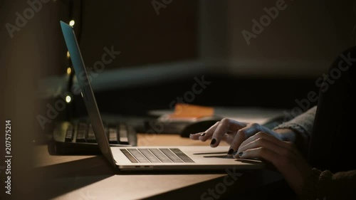 Close-up woman working with a laptop at night. Female hands using notebook touchbar and trackpad. Workaholic. 4K. photo