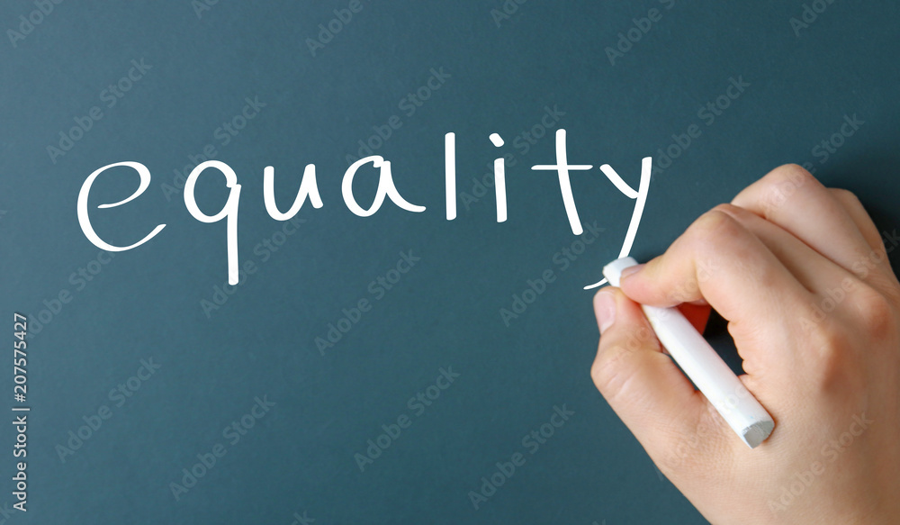 Green chalkboard with hand holding white chalk. Equality handwriting. Green chalkboard with hand holding white chalk. Equality handwriting.