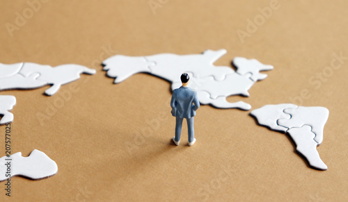 Among the world map puzzle the North American Map and standing miniature man. photo