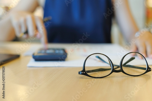 Close up eye glassess with Businesswoman analysis maketing plan background  Accountant calculate financial report with graph chart.  Business  Finance and Accounting concepts