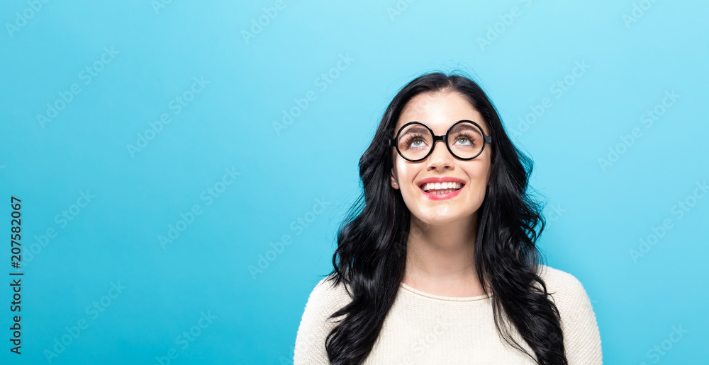 Young woman looking upward on a solid background - obrazy, fototapety, plakaty 