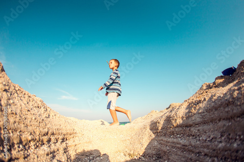 The boy walks along the sandy beach.