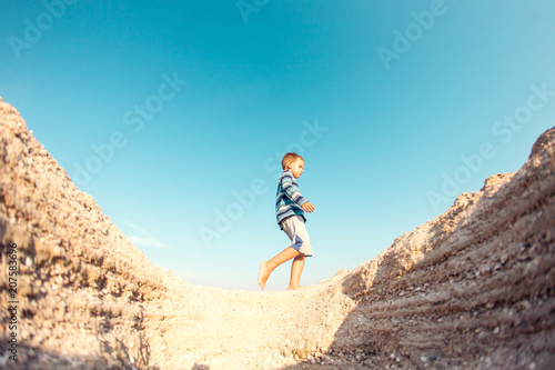 The boy walks along the sandy beach.