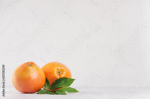 Two fresh glossy whole grapefruits on white wooden background with copy space. © finepoints