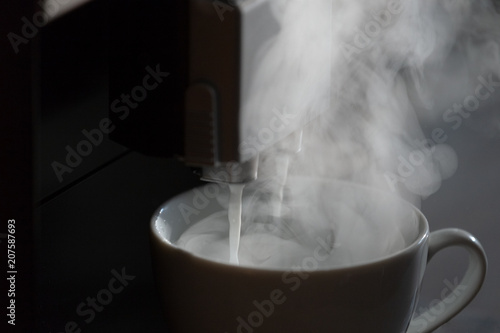 Black coffee in cup from coffee maker machine. Frothy foam