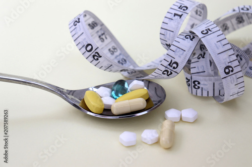 The pills on the silver spoon and the tape measure. photo