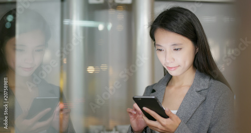 Business woman use of mobile phone with window reflection at night