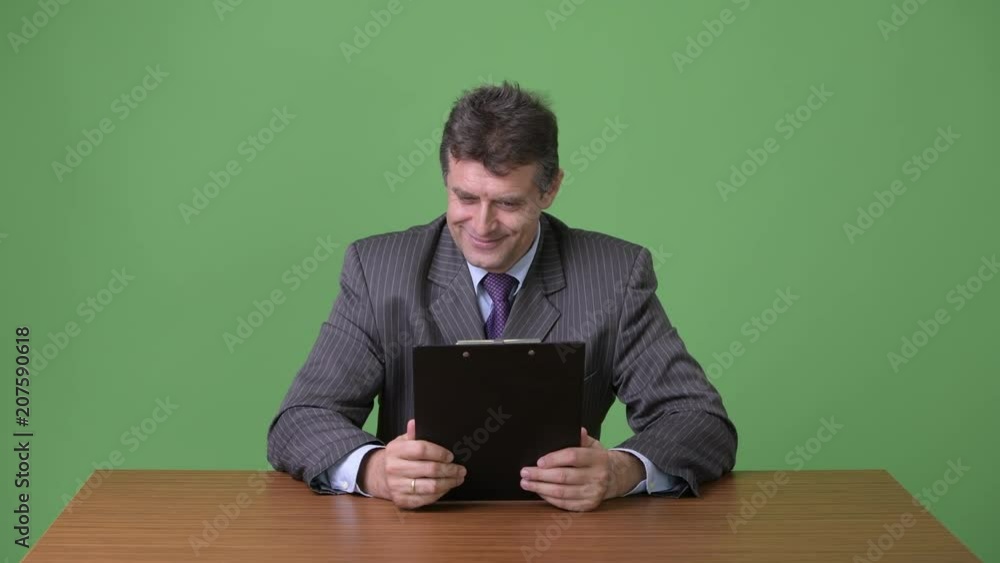 Mature handsome businessman against green background Mature handsome businessman against green background
