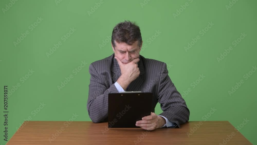 Mature handsome businessman against green background Mature handsome businessman against green background