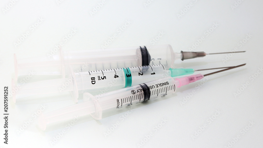 Three disposable medical syringes on a white background. Three disposable medical syringes on a white background.