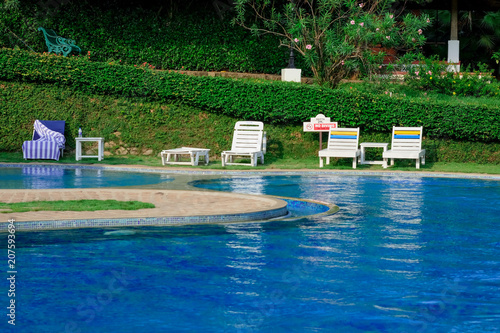 swimming pool and rest chair on background.