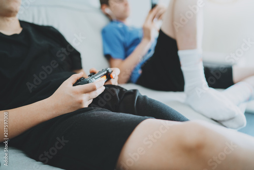 Brothers sitting on a sofa in living room and playing video games. Family relaxing time at home concept.