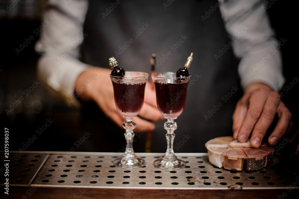 Bartender with two elegant glasses filled with sweet summer Arnaud cocktail